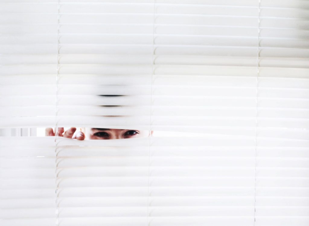 Image of person peaking through blinds